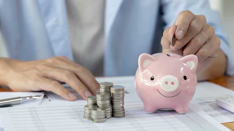 Man puts a coin in a piggy bank.