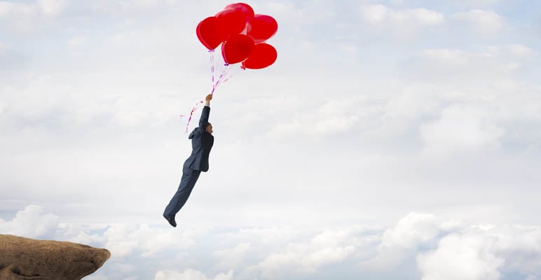 businessman flying upward with helium balloons