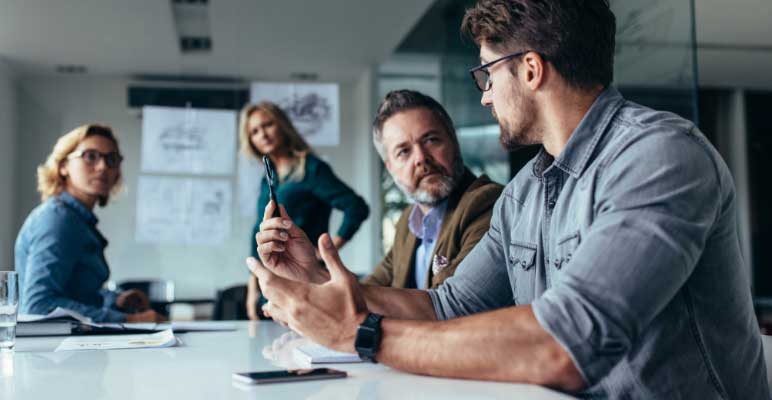 Two businessmen and two businesswomen in a conference room having a discussion.