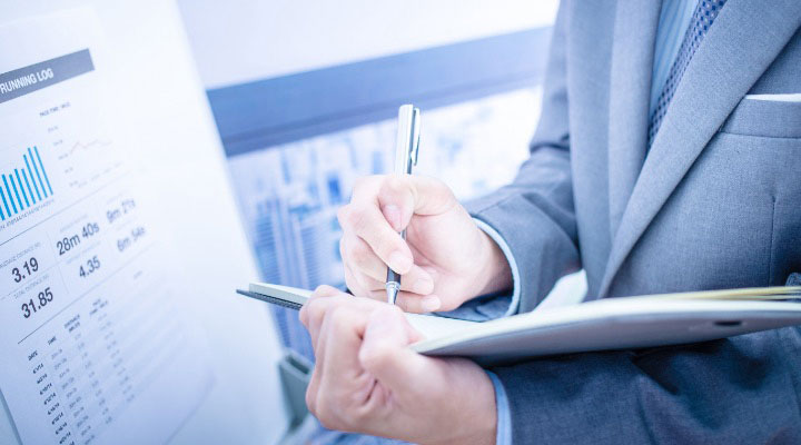 Businessperson analyzing charts and writing in folder.