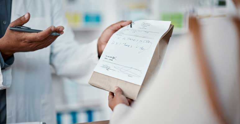 pharmacist hands with paper prescription with woman at counter