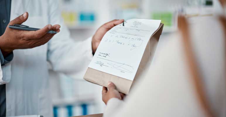 pharmacist hands with paper prescription with woman at counter